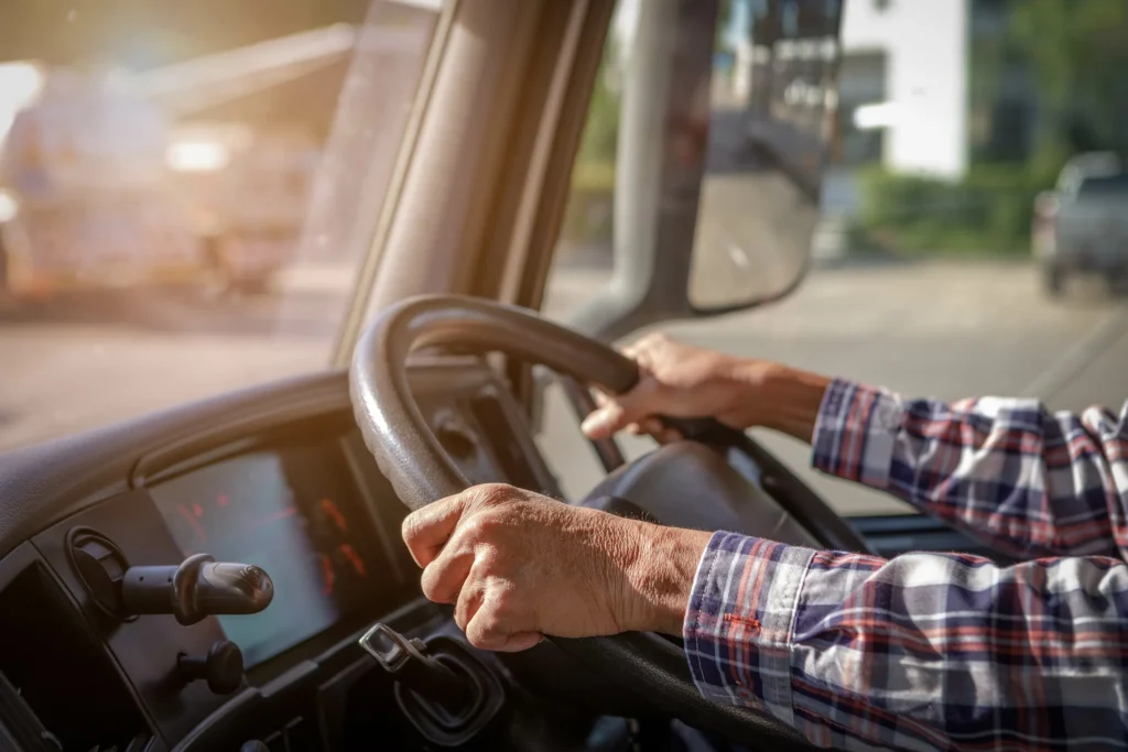 Close-up of a truck driver’s hands on the steering wheel of a commercial vehicle in El Paso, Texas.